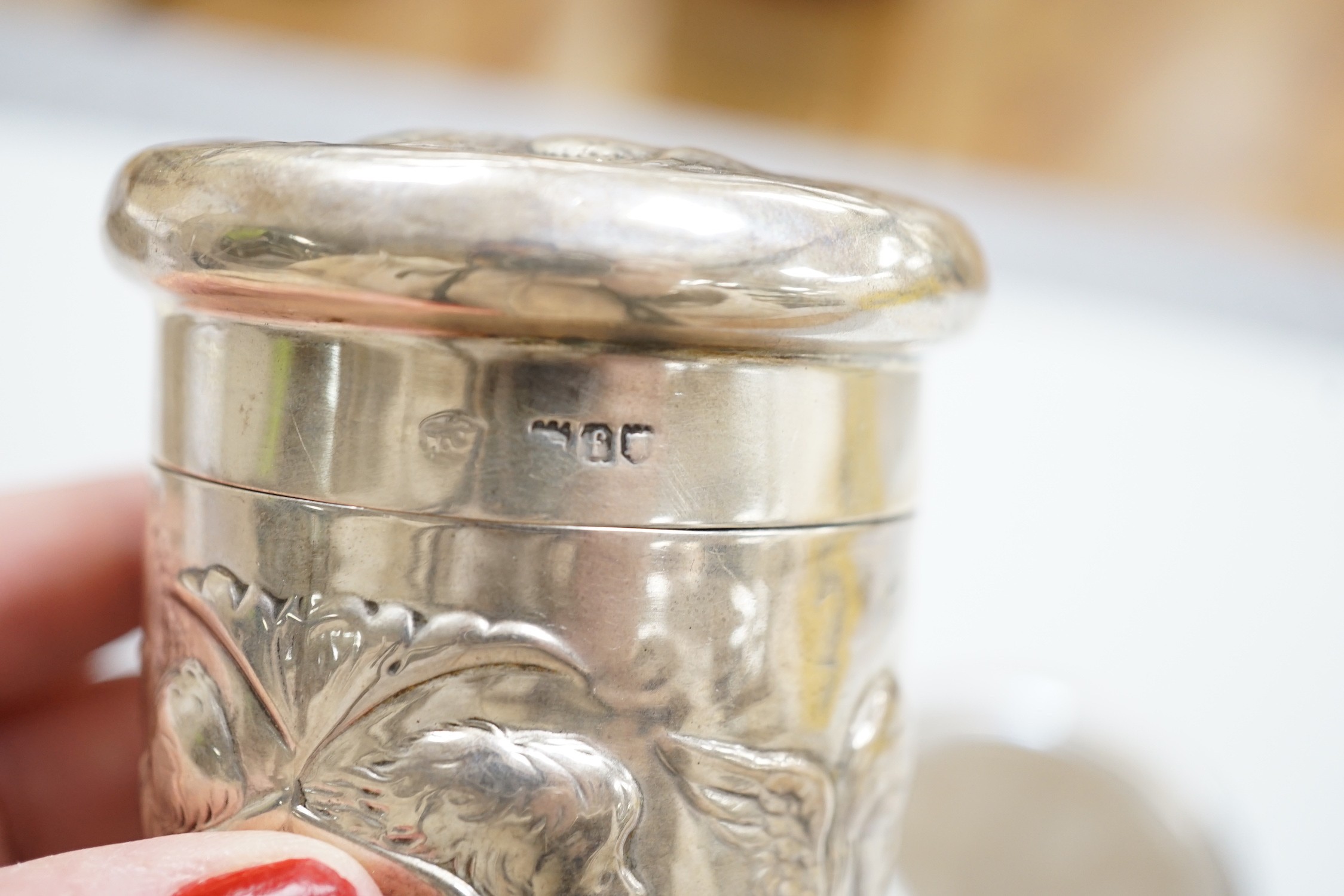 An Edwardian repousse silver Reynolds Angels toilet jar and cover, by William Comyns, London, 1901 and a later similar hand mirror by William Neale Ltd.